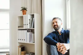 Businessman sitting against shelf